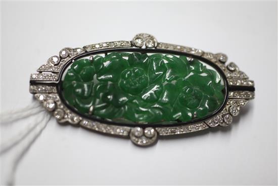 A 1920s/1930s Art Deco white gold?, pierced carved jadeite, diamond and black onyx set oval brooch, 53mm.